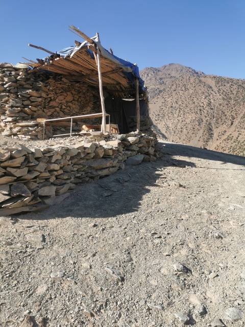 Rocky mountain path with a stone wall and small shelter.