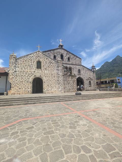 Stone church with a mountain backdrop and sunny weather