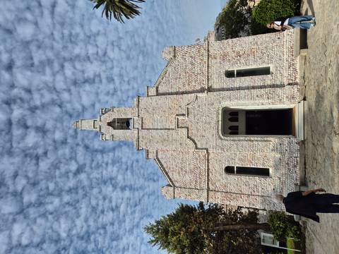 Building facade with shell patterns and people nearby.