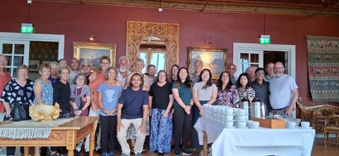       A large group of people posing in a room with ornate decor.
  