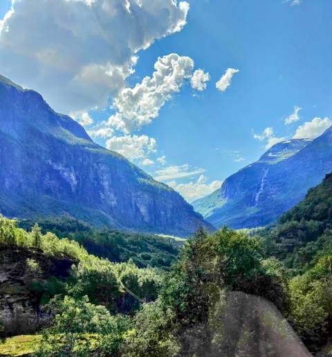       Mountainous landscape with lush trees and a clear sky.
  