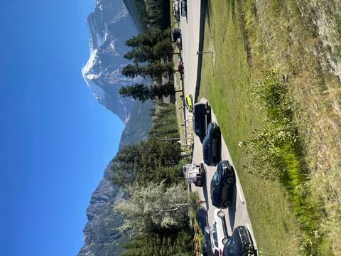 A parking area with cars and a snow-capped mountain in the background.