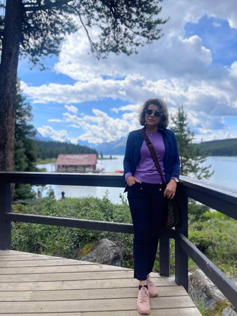 A person standing on a deck with lake and mountain views.
