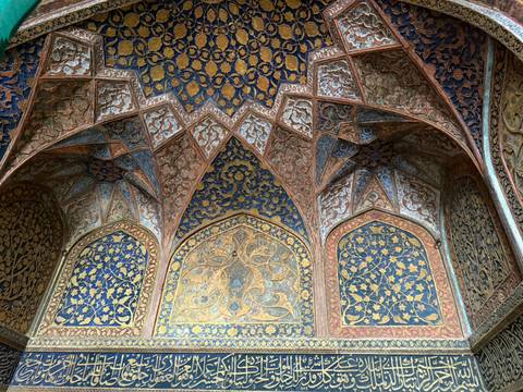 Intricately designed ceiling with colorful patterns, possibly from a historic site.
