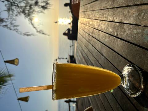 Refreshing drink on a table, with sunset over the ocean.