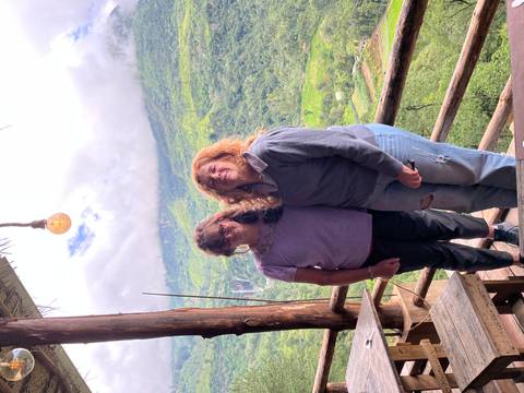 Two women posing with a scenic view of hills in the background.