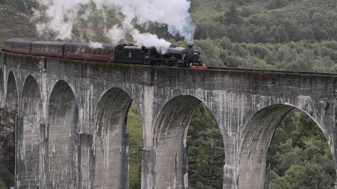Steam train crossing a large viaduct.