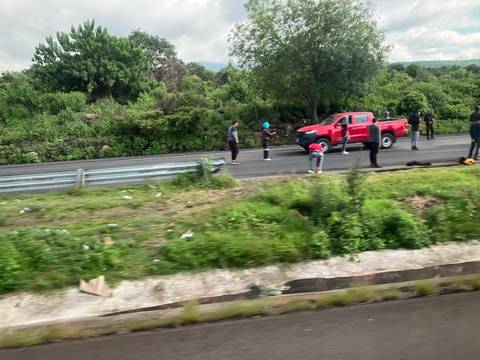 Roadside scene with people near a red pickup truck.