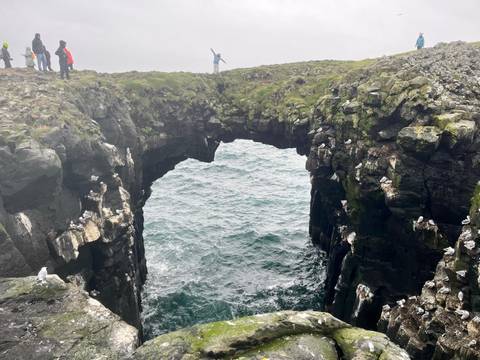 Natural rock bridge over the sea with birds.