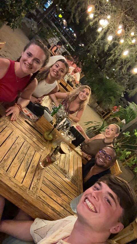 Group of friends enjoying drinks at a wooden table.