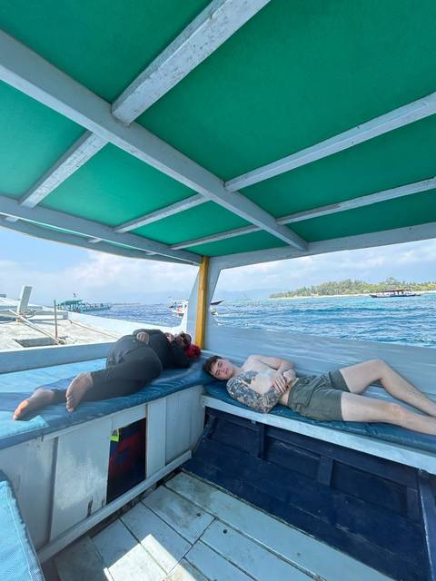 Two people relaxing on a boat near the coast.