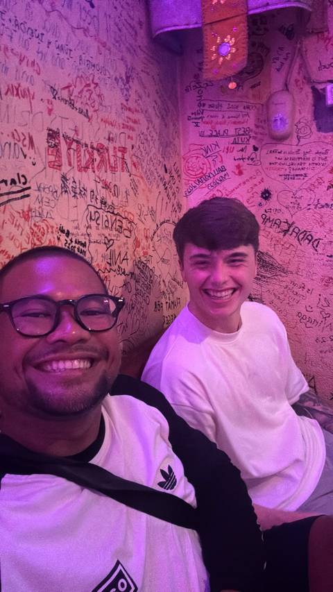 Two friends posing with graffiti on the wall.