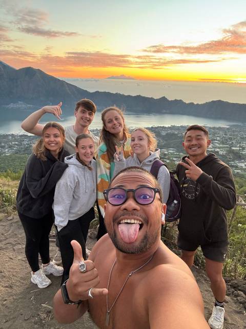 Group selfie with scenic view of a lake and town.