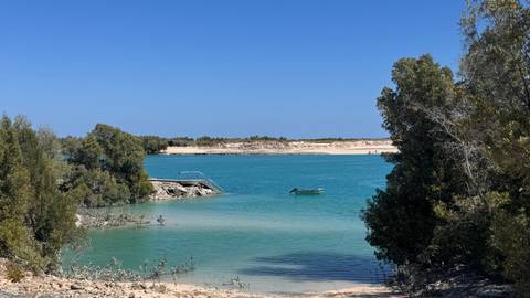 A calm bay with turquoise water and a boat.