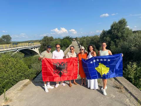 People holding Albanian and Kosovo flags on a bridge.