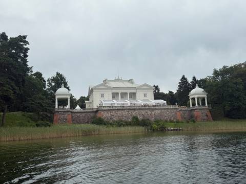       A white manor house on a small hill.
  