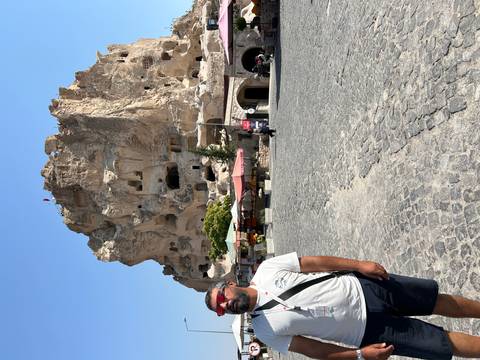       People near a rocky cliff with caves in Cappadocia.
  