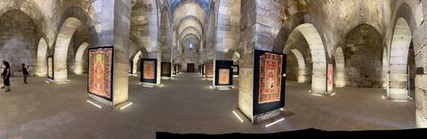       Exhibition with traditional carpets inside a historic building.
  