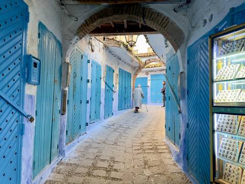 Blue painted alley with people walking.