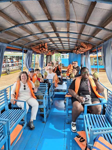       Group of people on a boat holding coconuts.
  