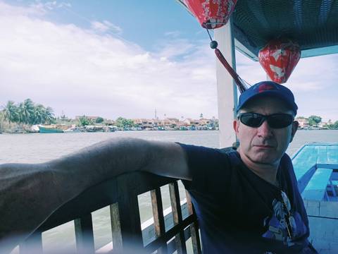       Man on a boat with a view of a waterfront town.
  
