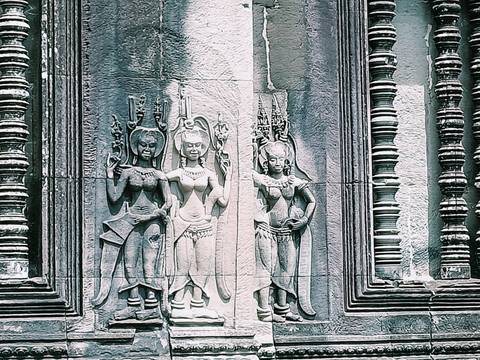       Stone carvings of dancers on a temple wall.
  