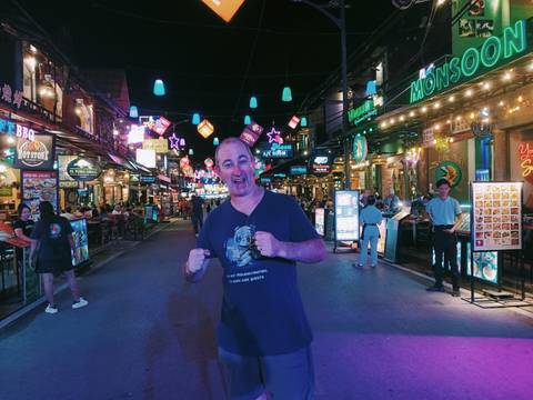       Man posing on a vibrant, illuminated street at night.
  