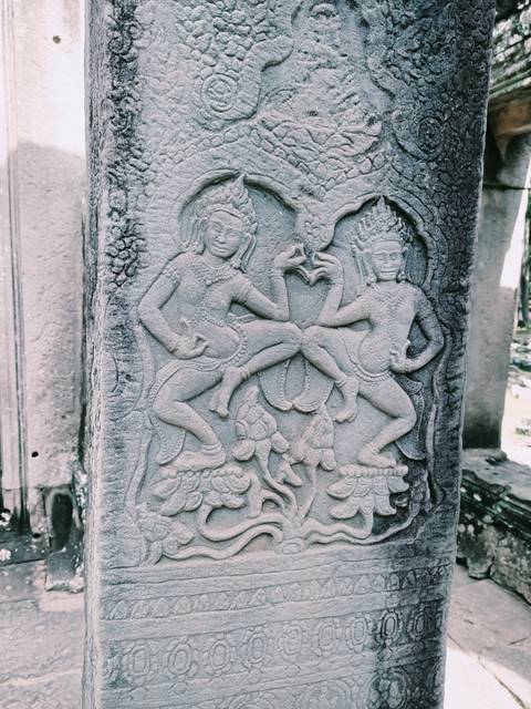       Stone carvings of dancers on a temple column.
  
