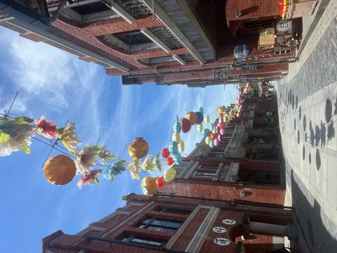 Street with colorful lanterns and brick buildings.