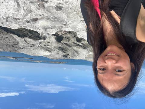 Woman taking a selfie by a rocky coastal area.