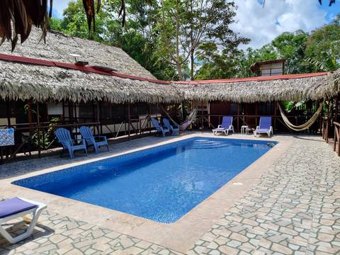       Pool surrounded by thatched buildings and hammocks.
  