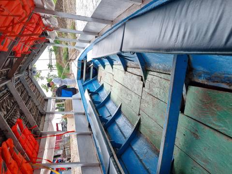       Open boat with benches and passengers boarding.
  