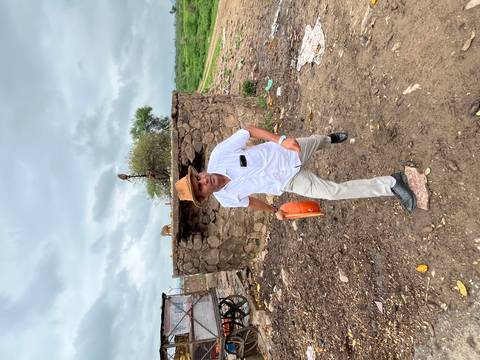 Man walking outdoors with a hat and a bag.