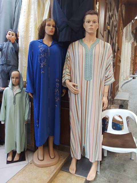       Traditional clothing displayed with a mannequin in a market.
  