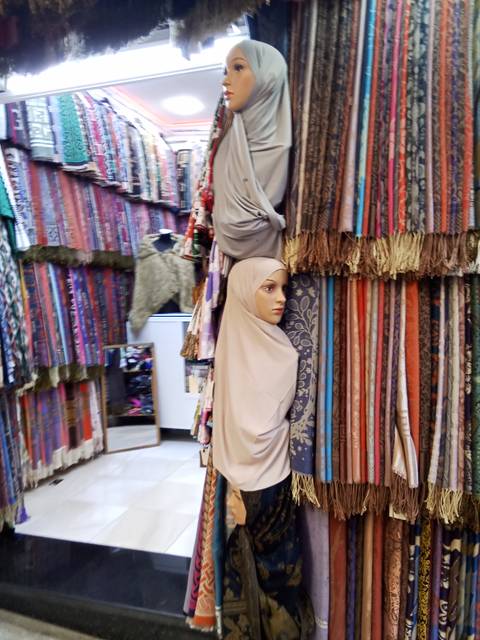       Market stall displaying traditional Moroccan attire and tiles.
  
