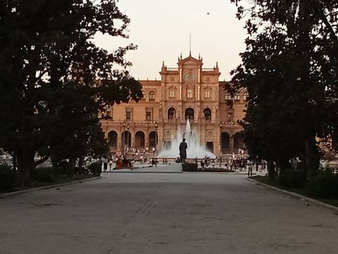       A path leading to a grand building with a fountain, trees line the pathway.
  