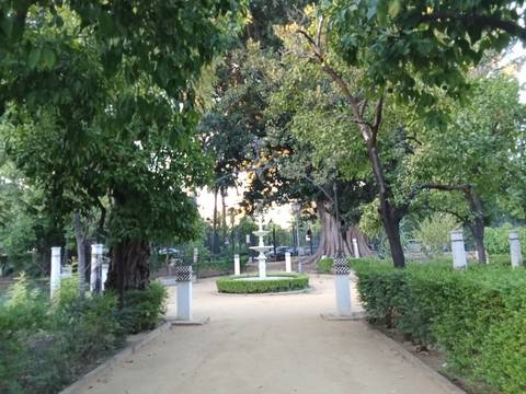       A serene garden scene with a small fountain and lush greenery.
  
