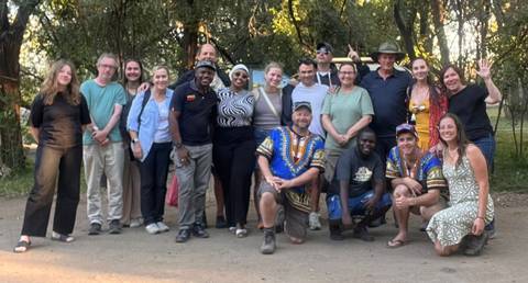 A group photo of 18 people smiling outdoors.