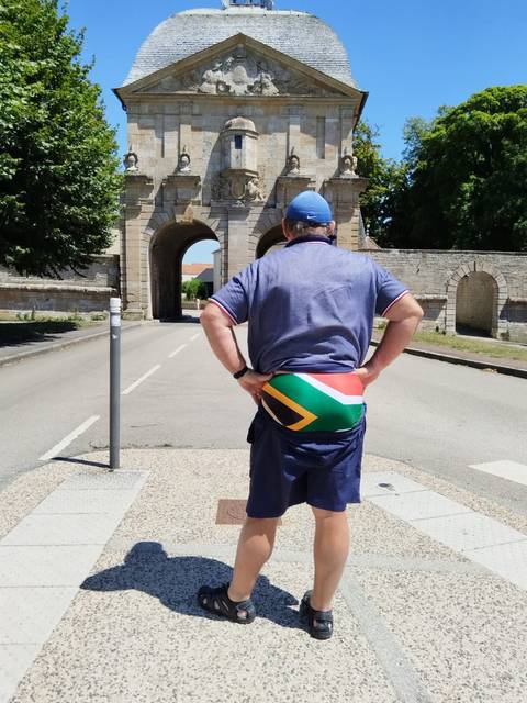 A man standing in front of a historic archway.