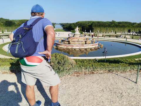 A man observing a fountain in a formal garden.