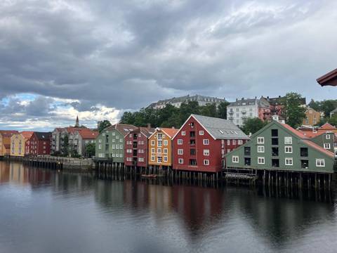 Colorful buildings lining a river with cloudy sky.