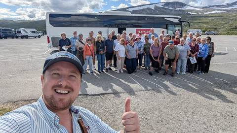 Group of people posing in a parking area with mountain in the background.