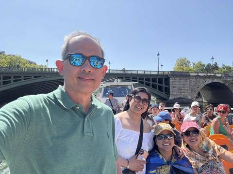 Tourists on a boat with a city bridge in the background.