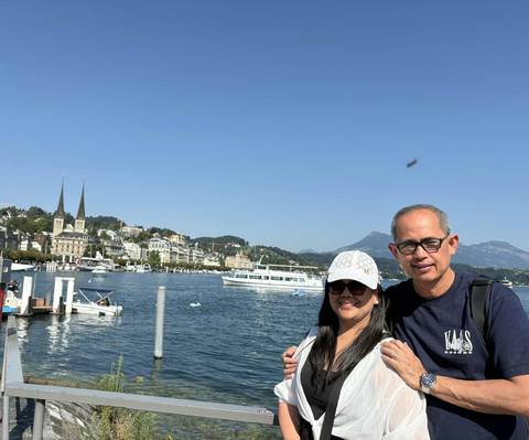       Couple posing by a lake with mountains in the background.
  