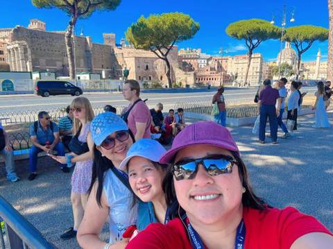       Group of women with ancient Roman ruins in the background.
  