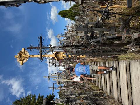       A group of people walking along a wooden path filled with crosses.
  