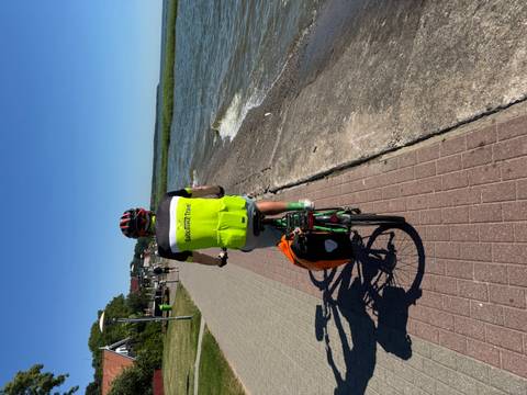 Cyclist on a path by the water on a clear day.