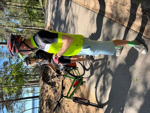 Two people with bicycles near a forest path with a lake view.