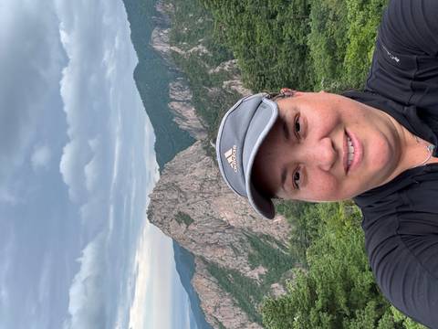       Person smiling with a mountain in the background.
  