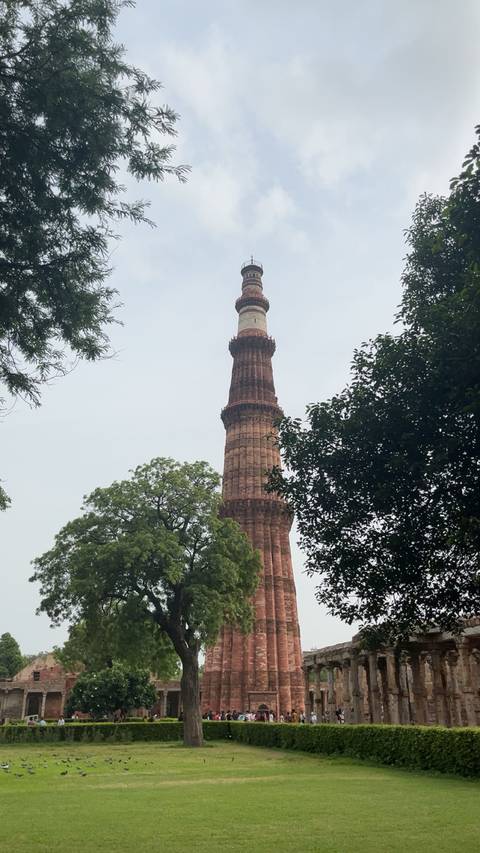 Tall red sandstone tower among trees.